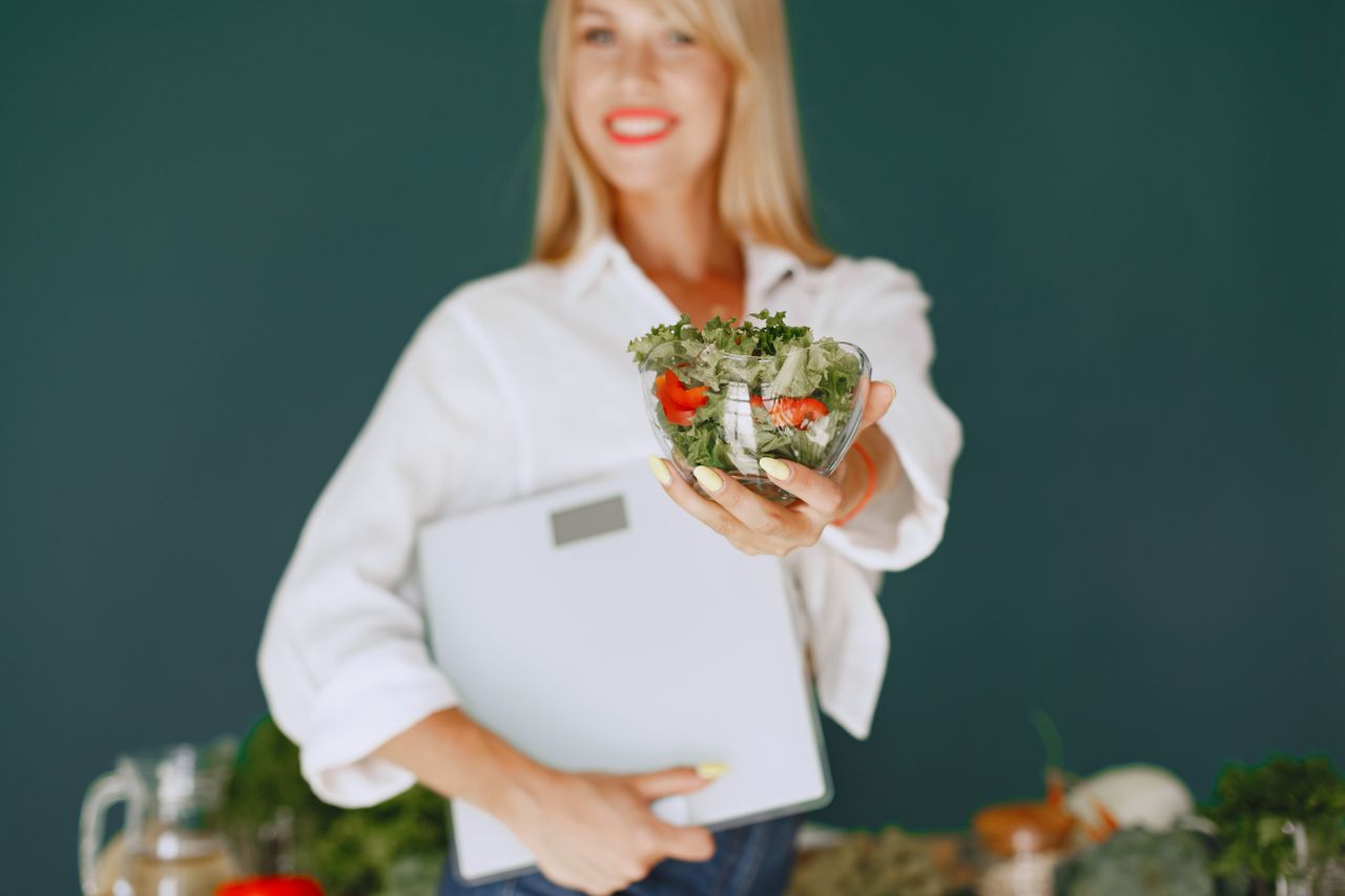 about-us A woman with a vibrant smile offering a fresh salad bowl, promoting healthy eating.