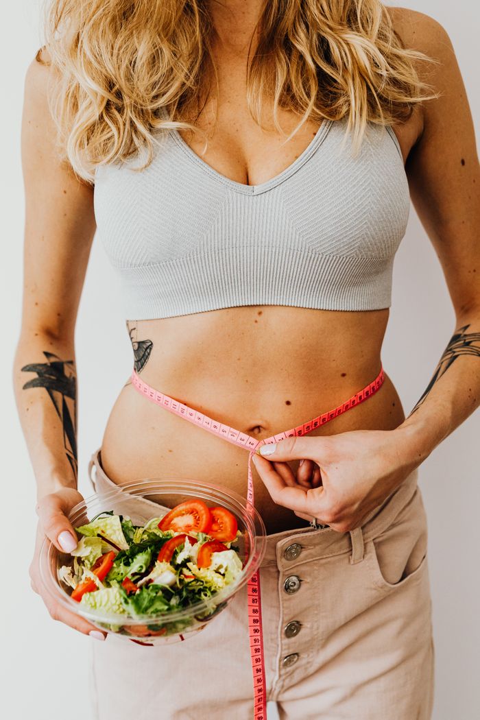 services-01 Fit woman in sports bra with salad and tape measure symbolizes healthy lifestyle. Ideal for weight loss themes.