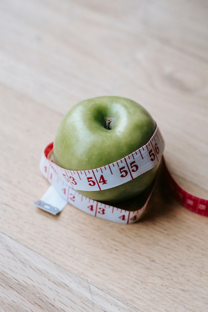 our-story From above of fresh healthy green apple tied with measuring tape placed on wooden table in daylight