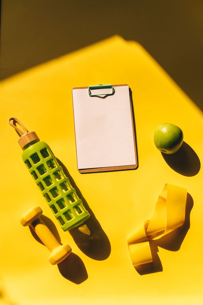 Crafting Captivating Headlines: Your awesome post title goes here Bright flat lay of fitness essentials including dumbbells, water bottle, and apple on a yellow background.